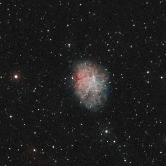 The Crab Nebula (M1) photographed from Lakeway, Texas with a ZWO Seestar S50 — a mottled oval of reddish filaments and a bluish interior glow, in a Taurus star field.
