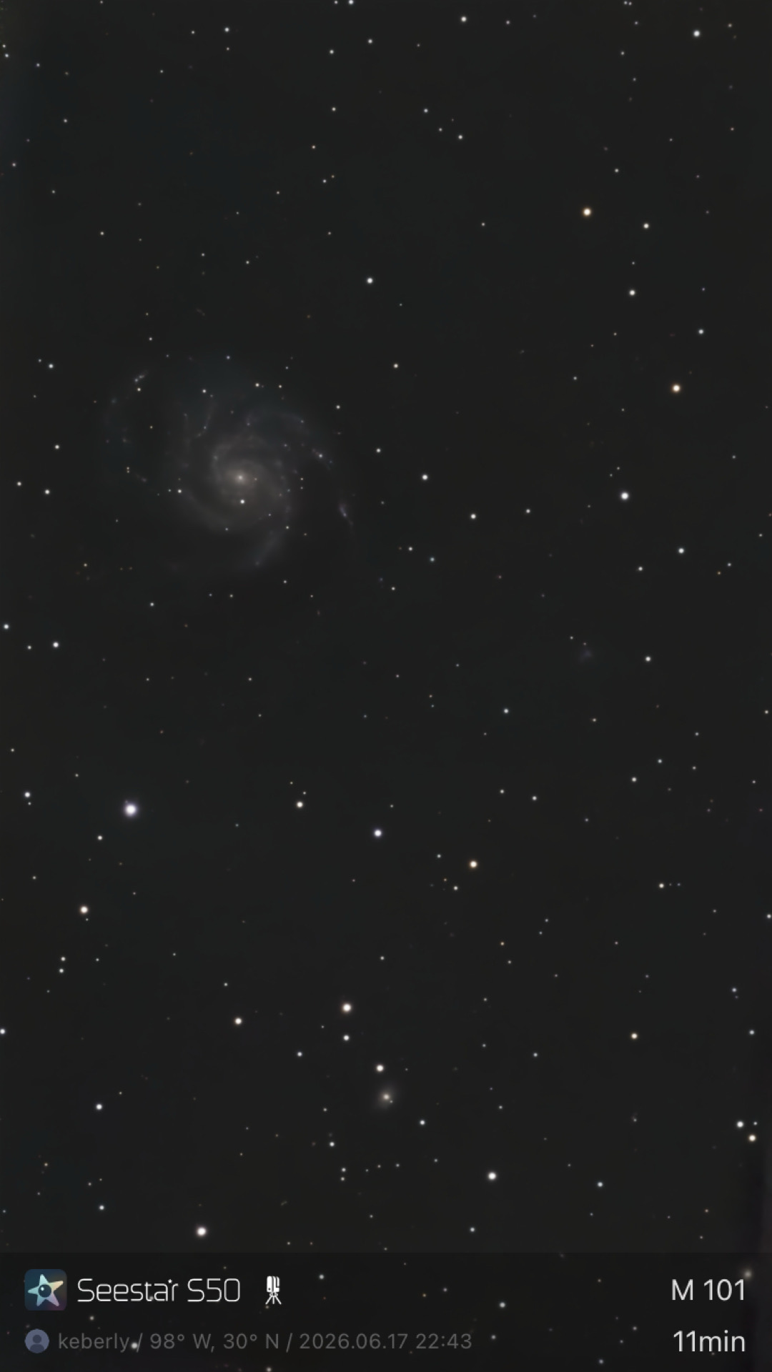 The Pinwheel Galaxy (M101) photographed from Bahía de los Ángeles, Baja California with a ZWO Seestar S50 in an 11-minute exposure — a face-on spiral galaxy with multiple clearly resolved arms in the upper-left of the frame, with a faint companion smudge visible in the lower section.