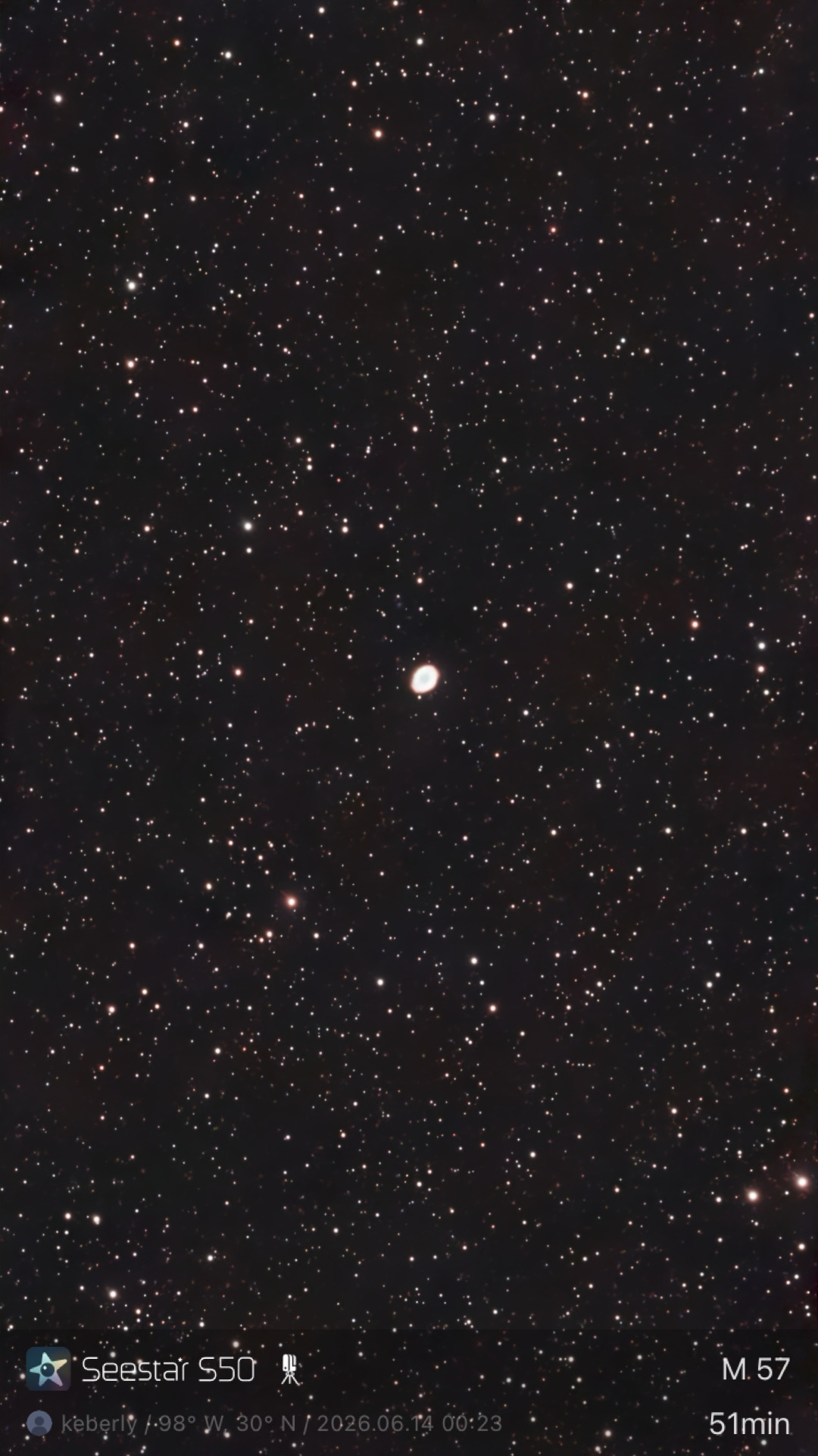 The Ring Nebula (M57) photographed from Lakeway, Texas with a ZWO Seestar S50 — a small but unmistakable elliptical ring with a cyan center and pinkish-white rim, set against a dense field of stars in the constellation Lyra.