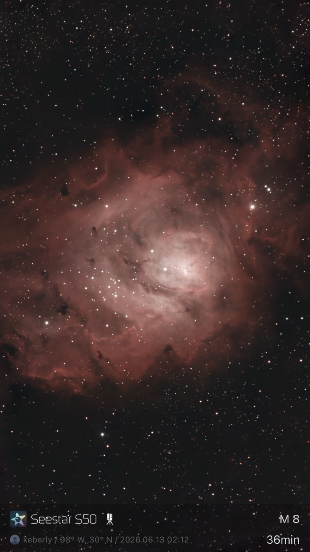The Lagoon Nebula (M8) photographed from Lakeway, Texas with a ZWO Seestar S50 — a large pink emission nebula with dark dust lanes cutting through and a bright central knot known as the Hourglass Nebula.
